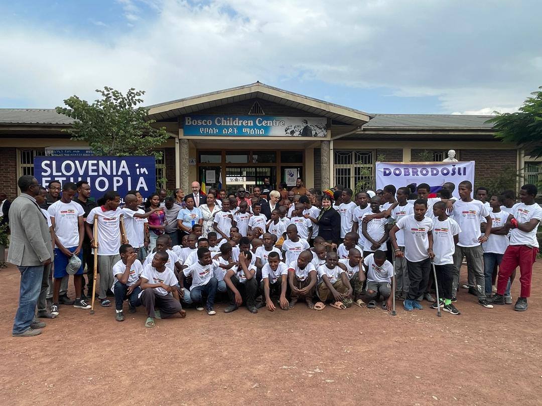 Morda je slika naslednjega: ‎3 osebe in ‎besedilo, ki pravi »‎Children ChildrenCentre Centre የመስኮልጆችማለከል የቦስኮ ልደች ማዕከል SLOVENIA in ΕΤΨ باز 4e e 生イ元屋 DOBRODOŚLI T‎«‎‎